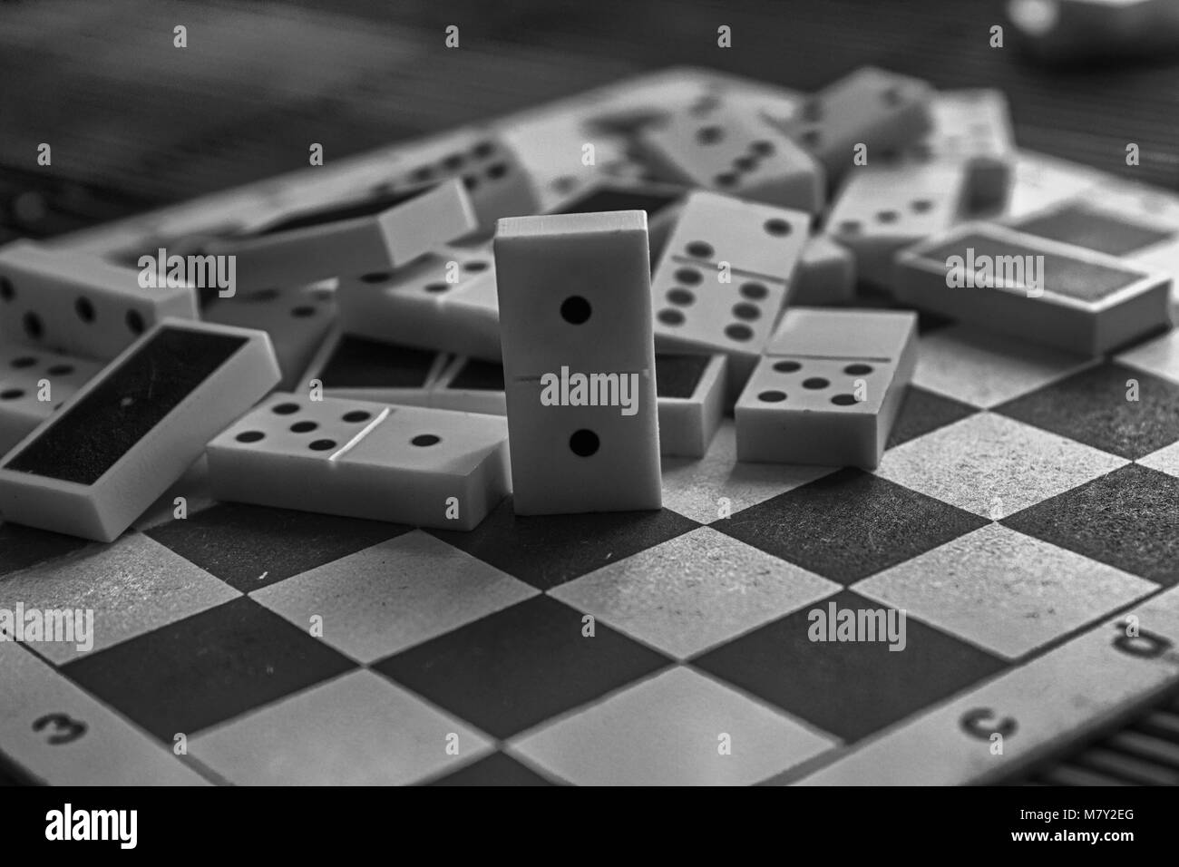 Monochrome Chaotic pile of domino pieces on the bamboo brown wooden table background Stock Photo