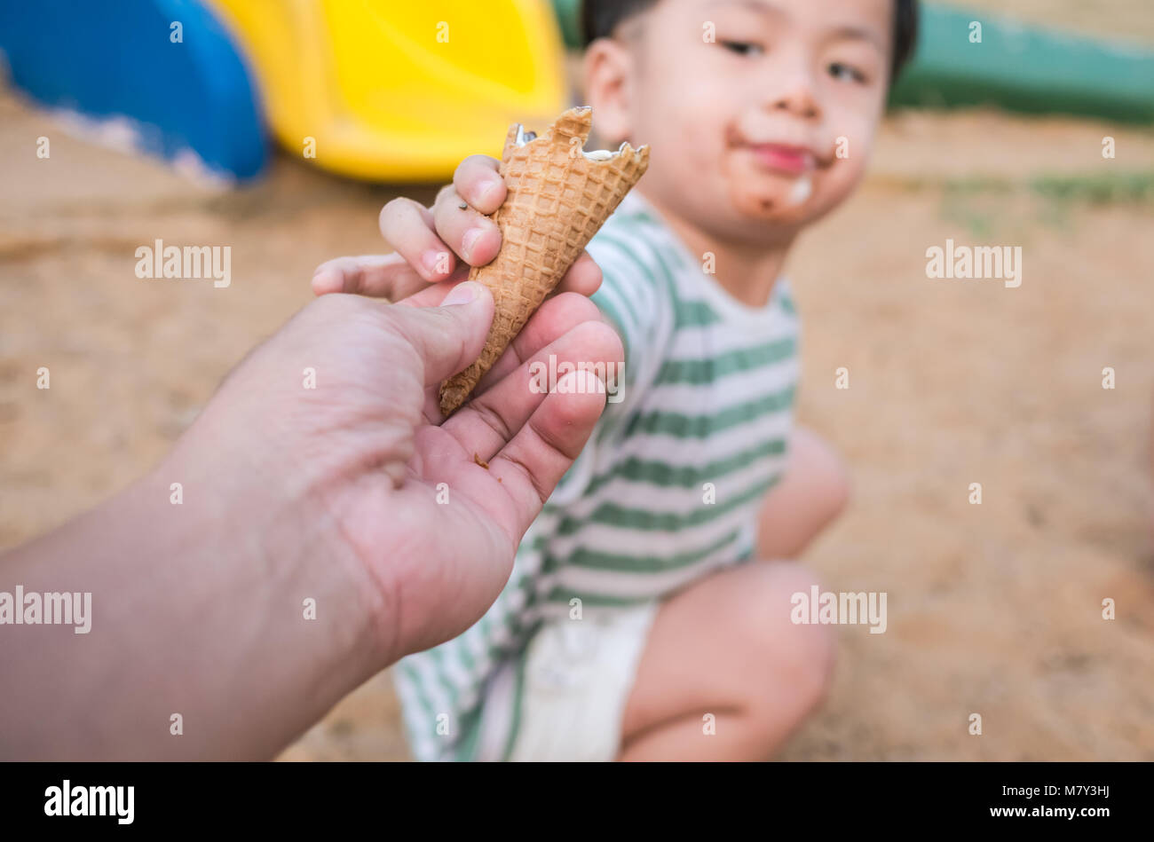 Close up of man hand and little boy hand holding fresh waffle cone, eat ice cream half-cone on baby background, Stock Photo