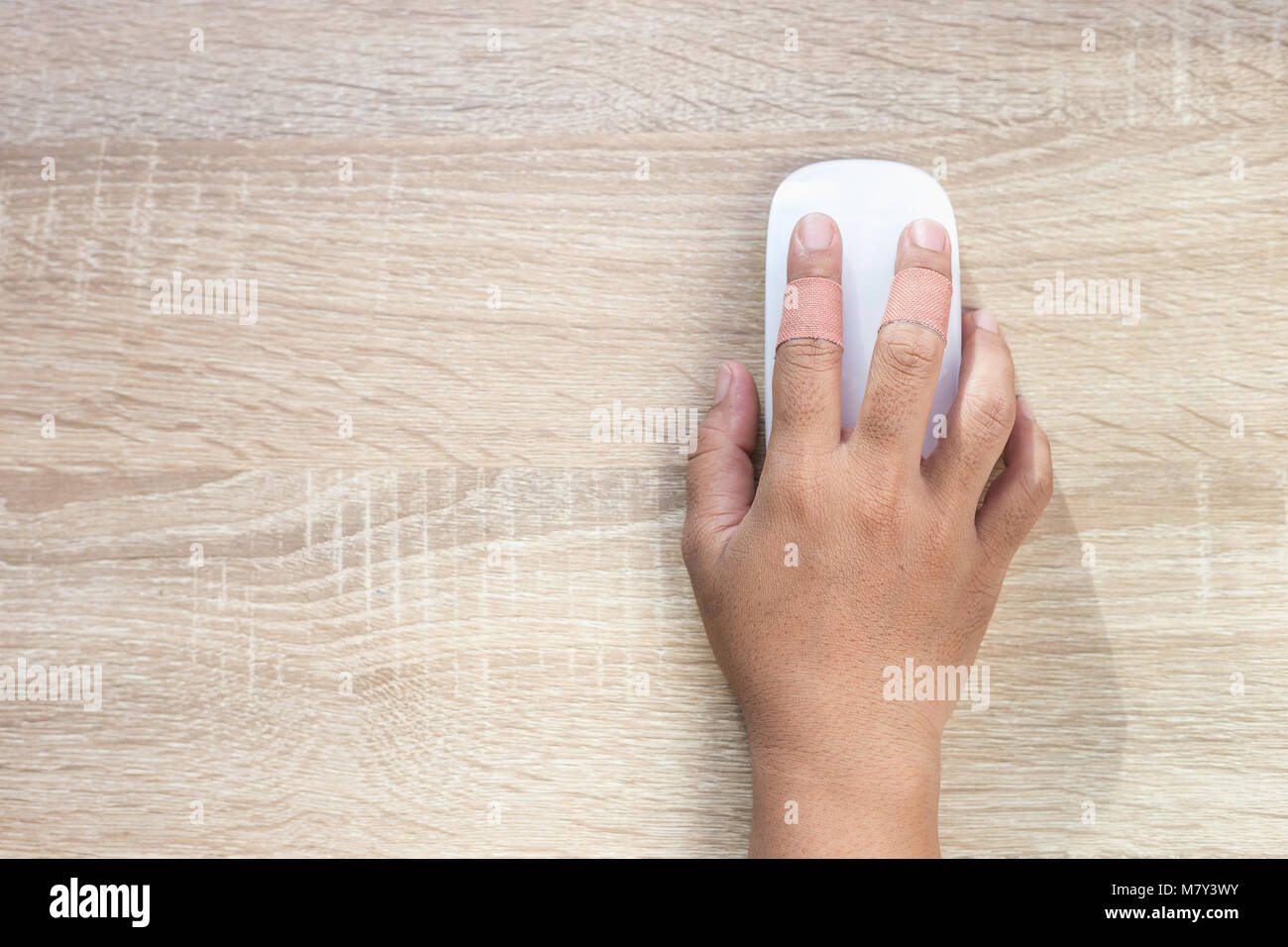 Top view hand with injury on finger using white computer wireless mouse on wooden background Stock Photo