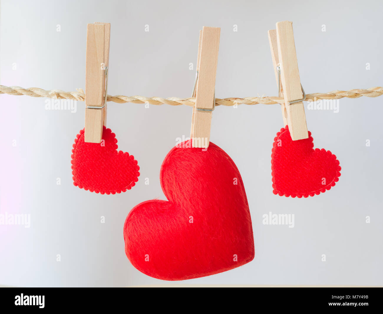 Red heart attached to a clothesline with pin on white background, Stock Photo