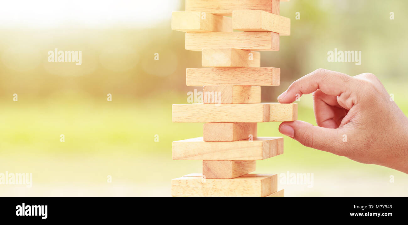 Close up hand holding blocks wood game on blurred green background. With copy space for text or design concept Stock Photo