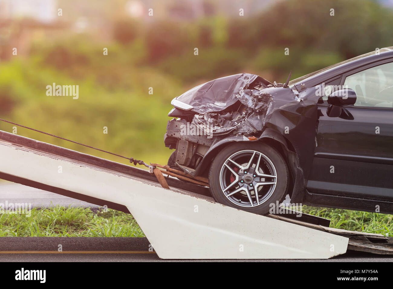 Front of black car get damaged by accident on the road. And moving to the truck for repair Stock Photo