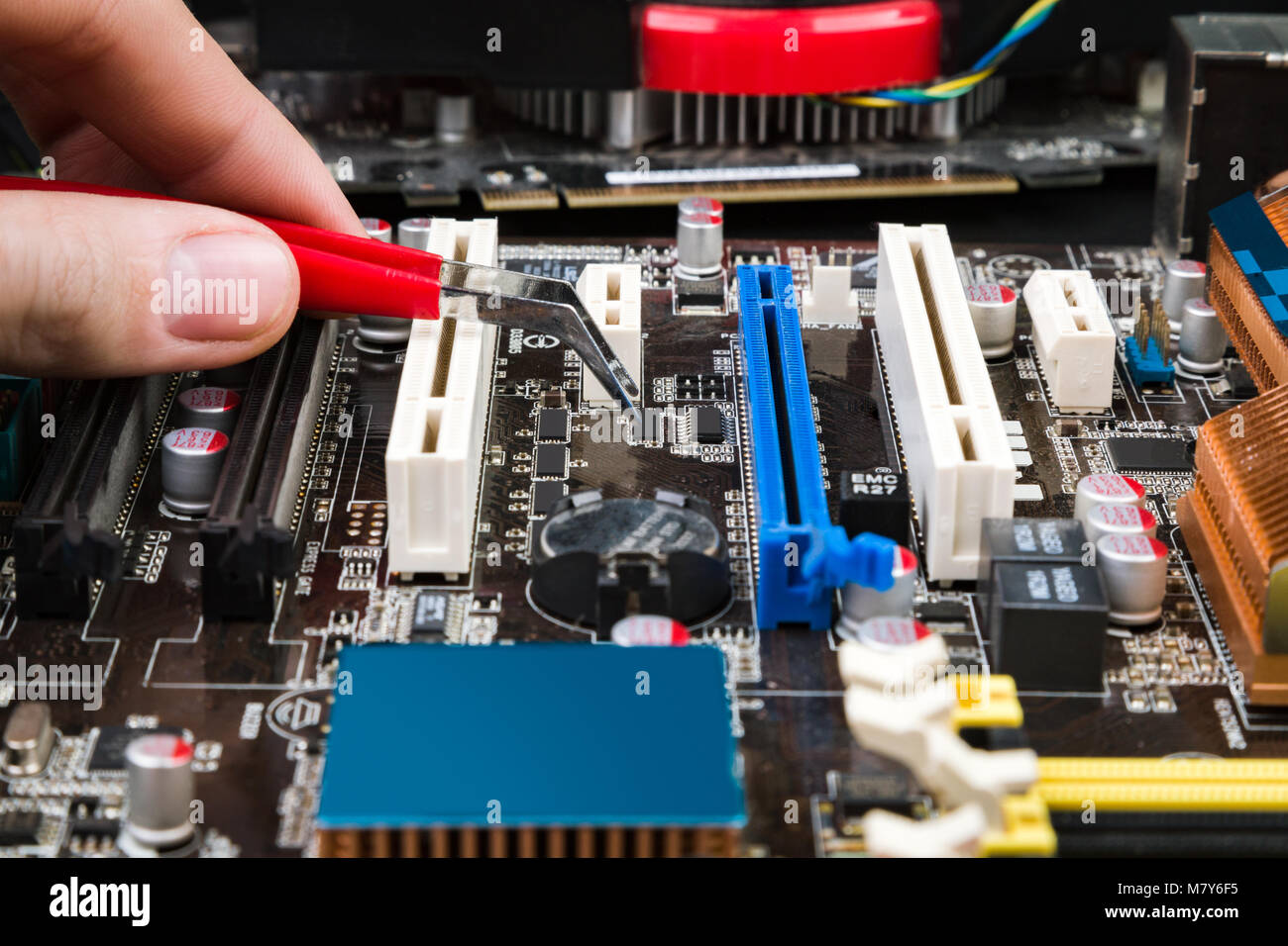 Fix and restore the old game motherboard with tweezers on a black table