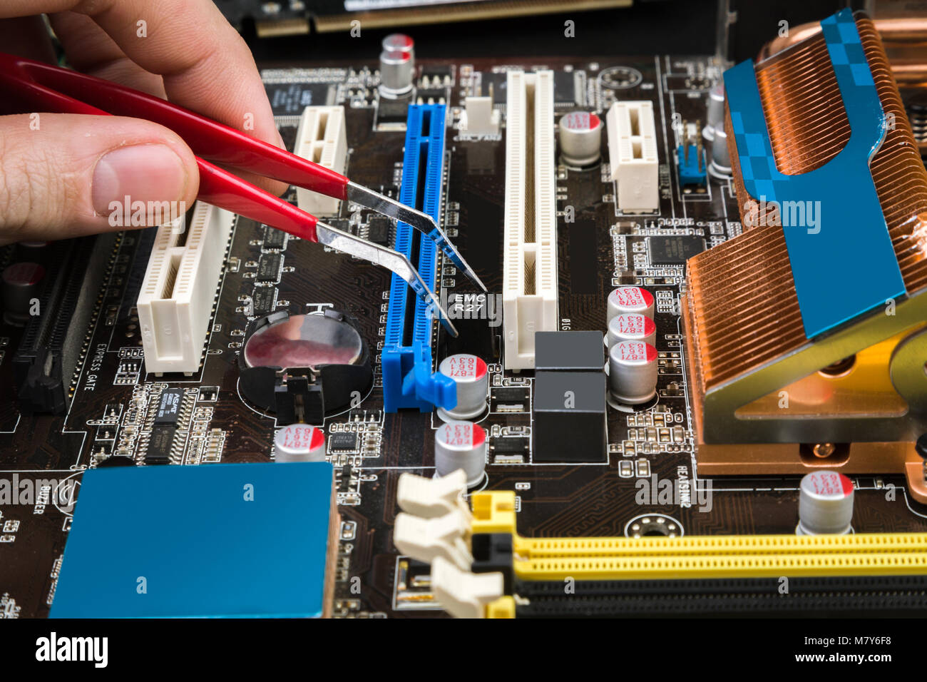 Fix and restore the old game motherboard with tweezers on a black table.  Workplace repairman computers Stock Photo - Alamy