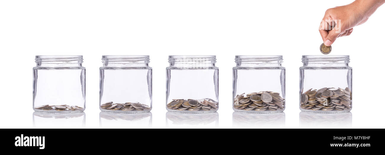 Hand holding Thai coin (baht) and insert to clear glass jar. Studio shot isolated on white background. Save money or investment financial for future c Stock Photo