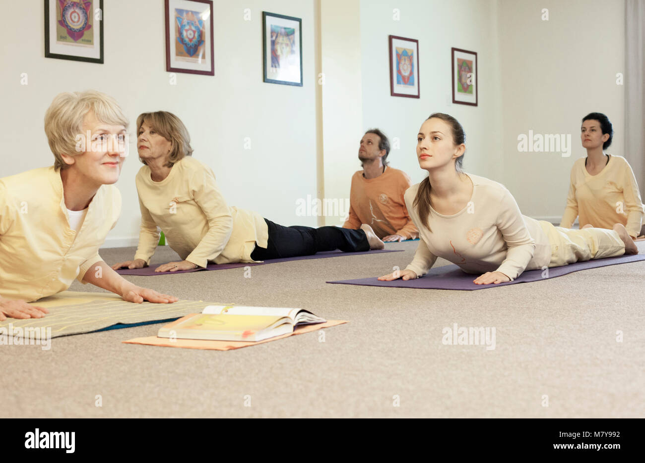 People practising bhujanga asana cobra pose in yoga class in attic