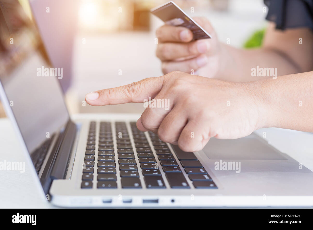 Close up woman hands holding credit card in front of laptop on the desk. Easy way online shopping concept Stock Photo