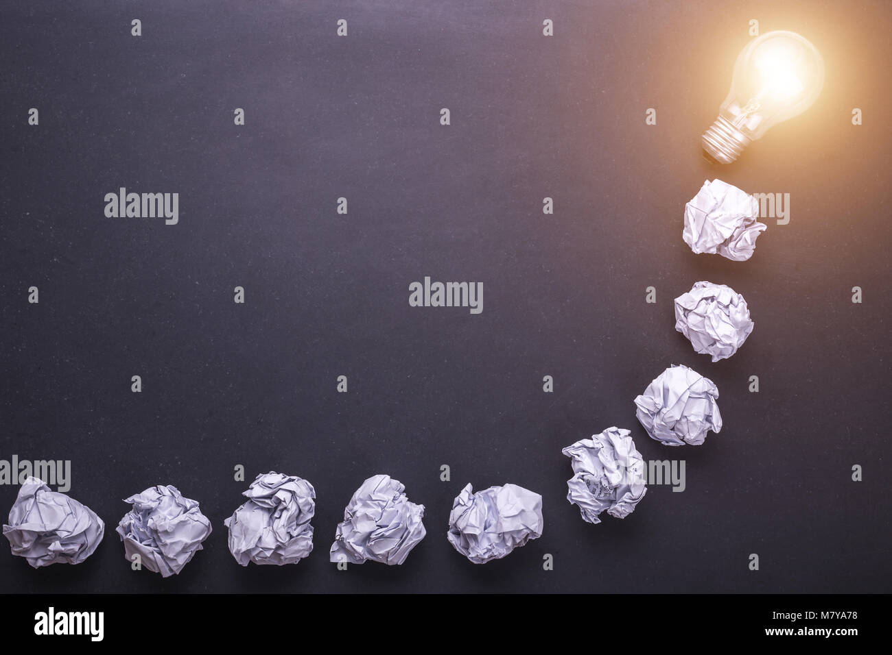 Top view crumpled white paper and light bulbs on black stone board. Create idea concept Stock Photo