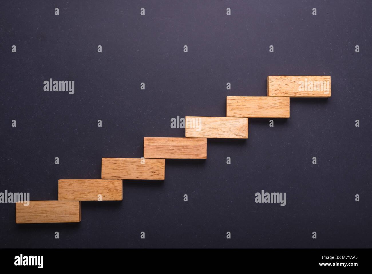 Top view wooden block set up for staircase on black stone board. Business concept for growth success process. Stock Photo