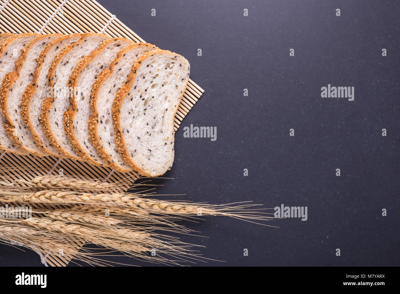 Slices of fresh white bread with sesame seeds on black stone table ...