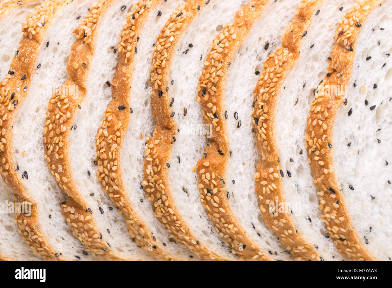 Slices of fresh white bread with sesame seeds on black stone table ...