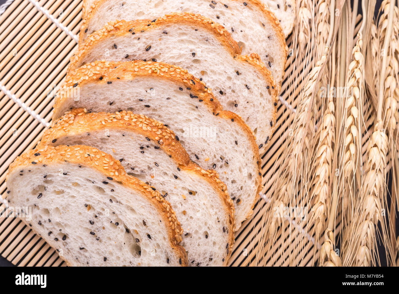 Slices of fresh white bread with sesame seeds on black stone table ...