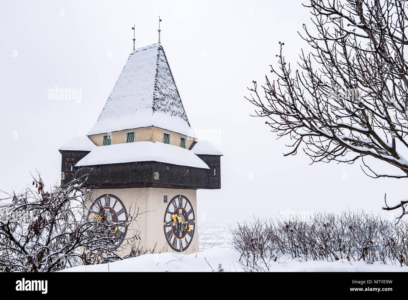 Snow covered Uhrturm clocktower landmark of city Graz on hill Schlossberg in winter Stock Photo
