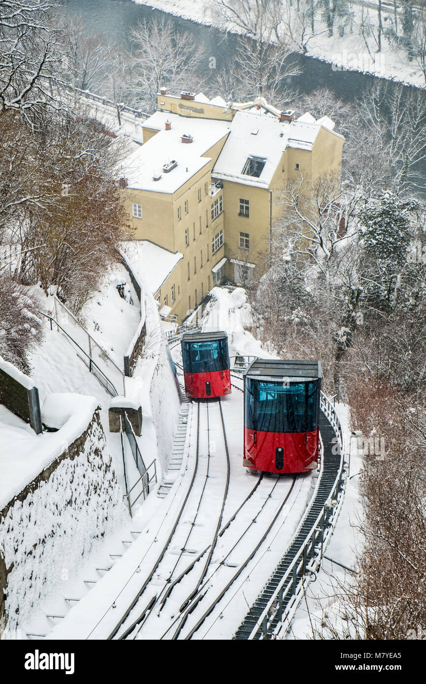 Red funicular railway cable car on hill Schlossberg with aerial view to snow covered city Graz in winter Stock Photo