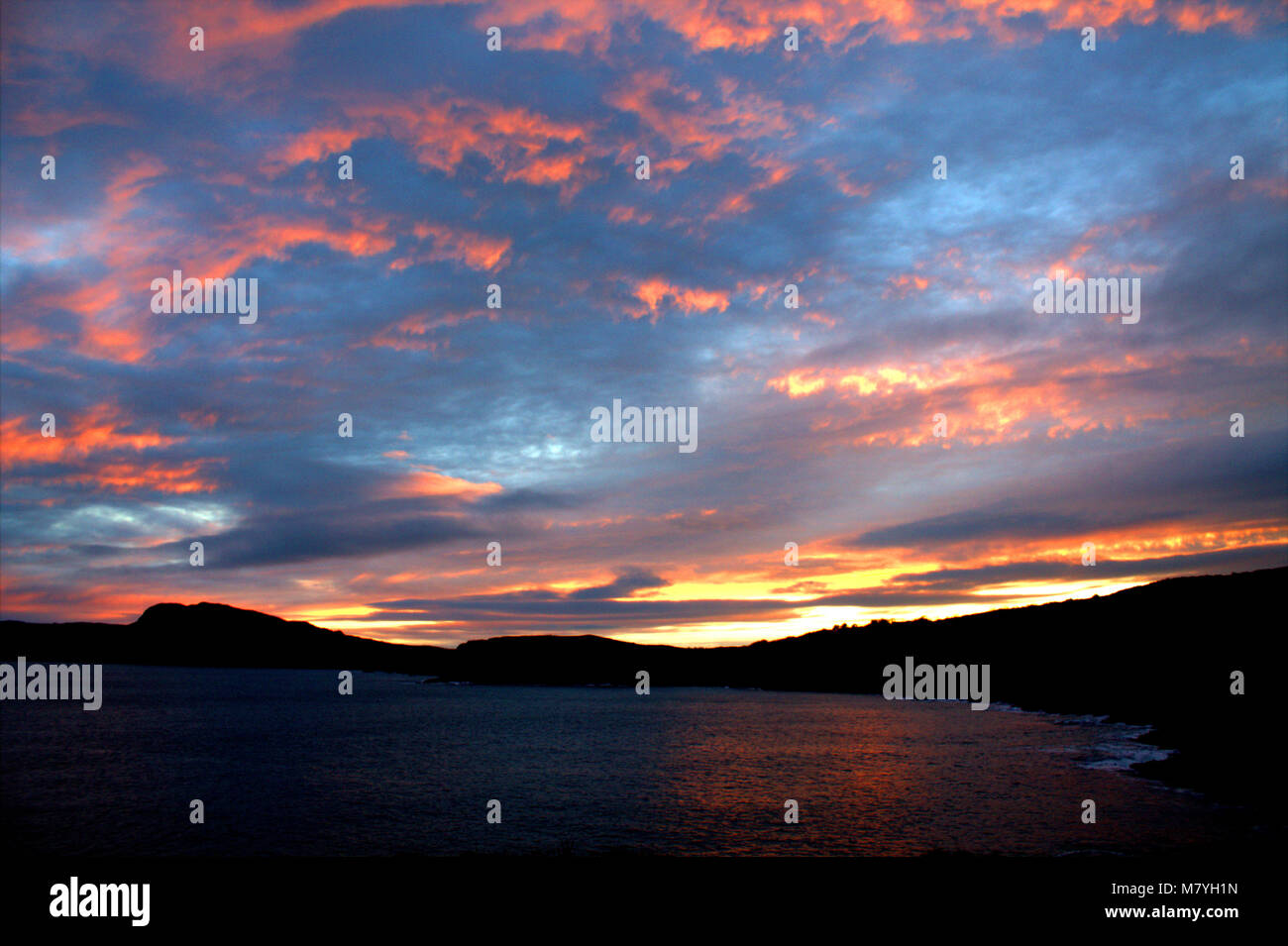 blood red sky caused by last rays of sunset behind sea cliffs of sandy cove, west cork, ireland. Stock Photo