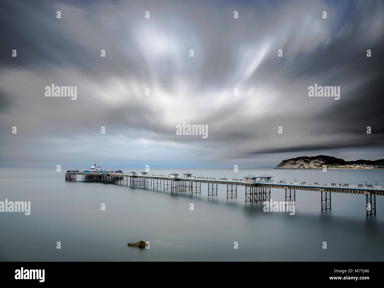 Llandudno pier under cloudy skies on the North Wales coast with motion blur on the sky and sea Stock Photo