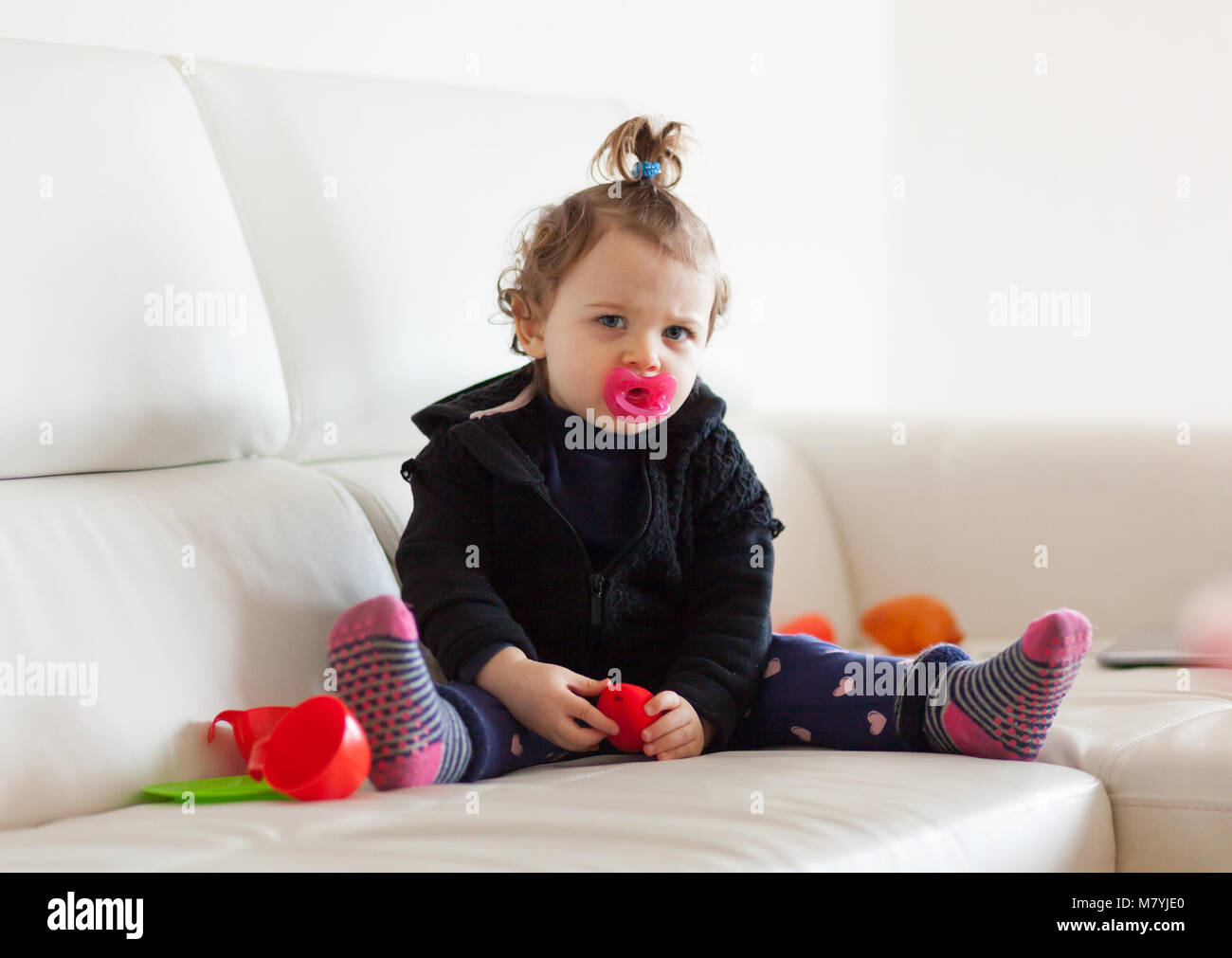 Portrait of cute toddler baby girl playing on the sofa. Stock Photo