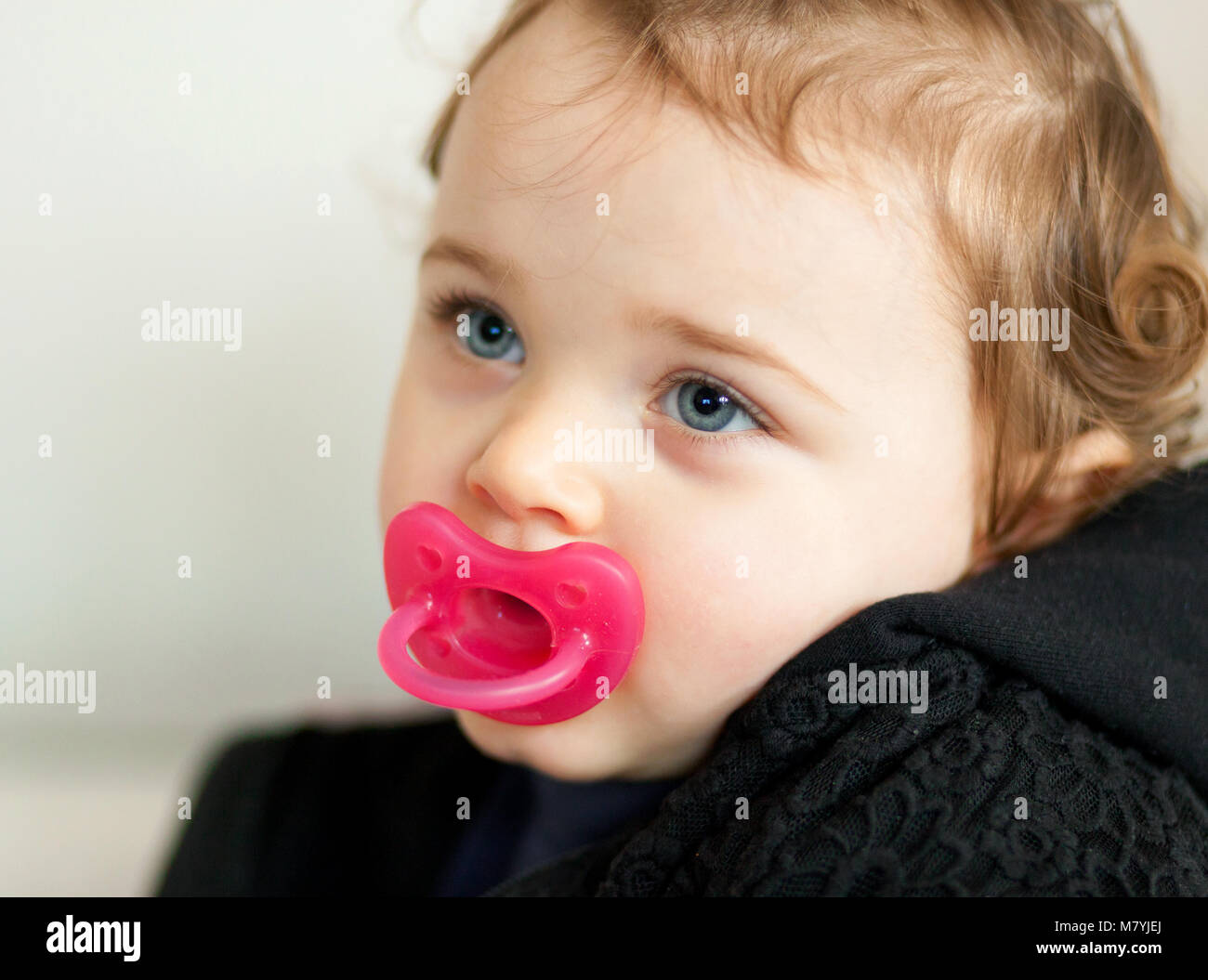 Portrait of cute toddler baby girl playing on the sofa. Stock Photo