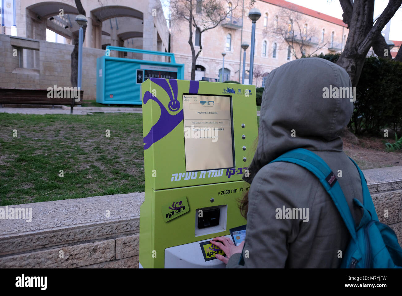 A young woman using an electronic contactless card reader machine to recharge a Rav-Kav  'smart card' which is a form of electronic ticketing used in all bus companies and the national railway in Israel. Jaffa road West Jerusalem Stock Photo