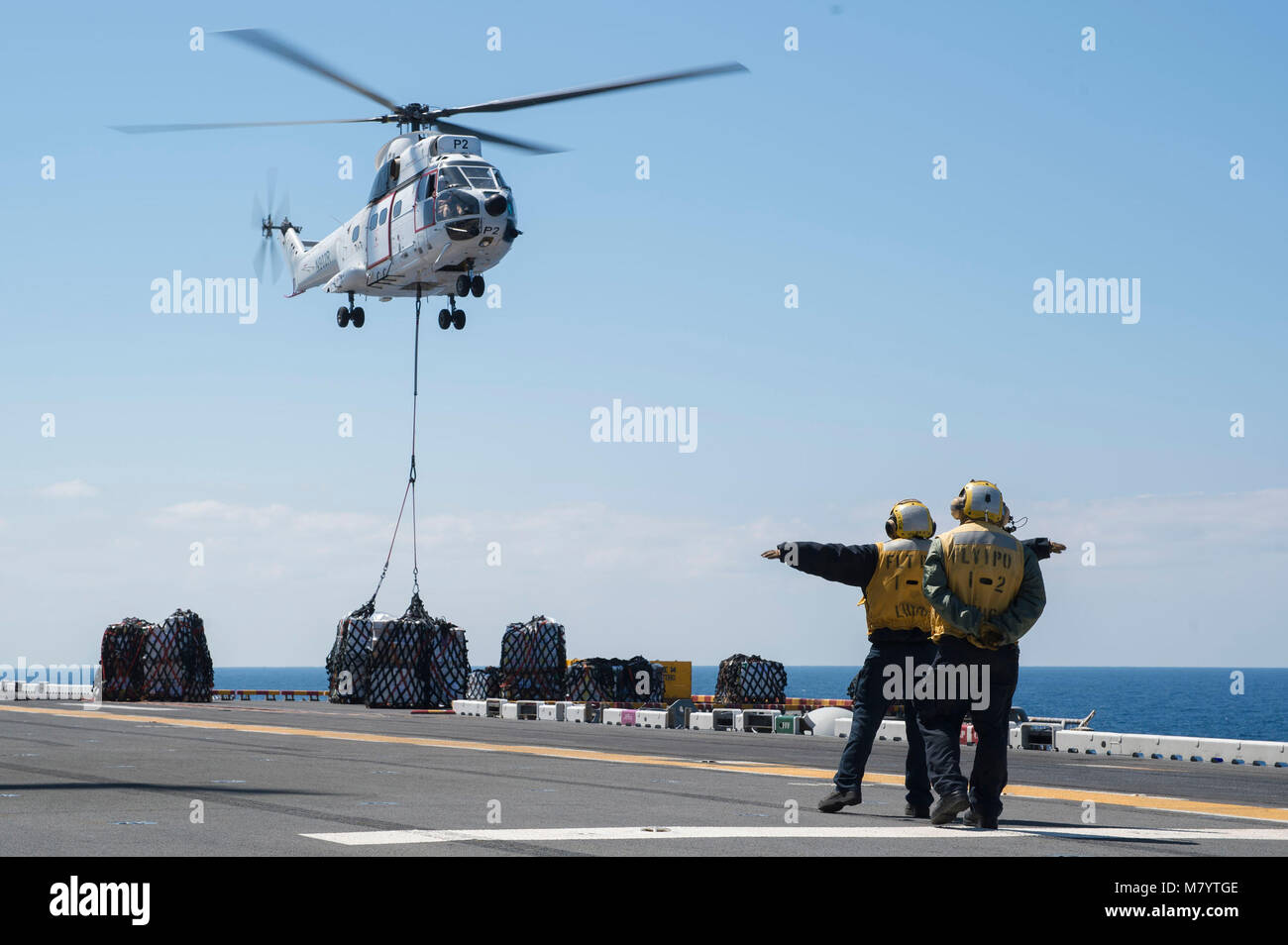 180311-N-RD713-008 PHILIPPINE SEA (March 11, 2018) Airman Apprentice Elizabeth Ramirez, left, from Reno, Nev., and Aviation Boatswain’s Mate (Handling) 2nd Class Genesis Monta, from San Diego, direct an AS-322 Super Puma helicopter, assigned to the dry cargo and ammunition ship  USNS Cesar Chavez (T-AKE 14), on the flight deck of the amphibious assault ship USS Bonhomme Richard (LHD 6) during a replenishment-at-sea. Bonhomme Richard is operating in the Indo-Pacific region as part of a regularly scheduled patrol and provides a rapid-response capability in the event of a regional contingency or  Stock Photo