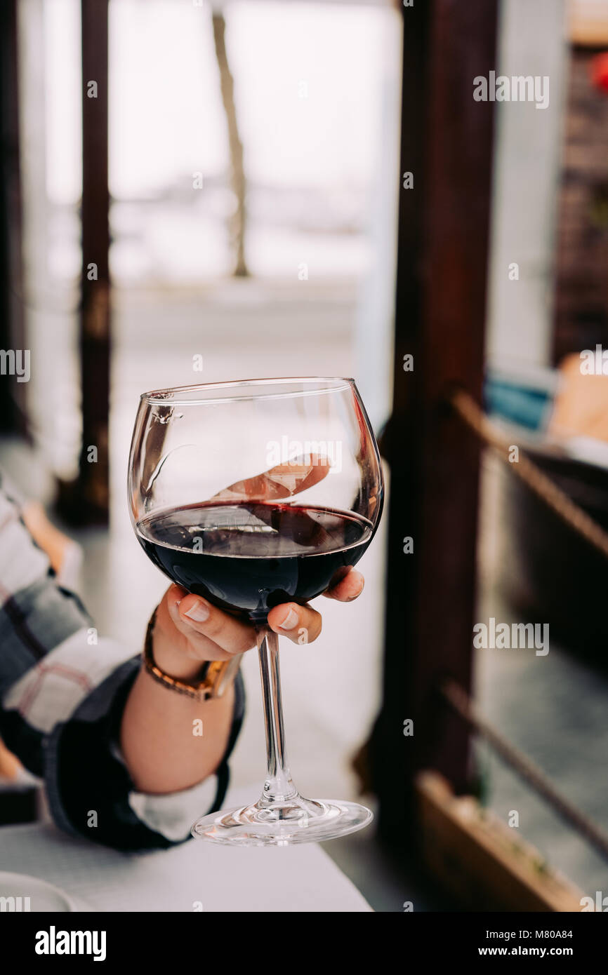 Woman hand holding a wine glass with red wine Stock Photo - Alamy