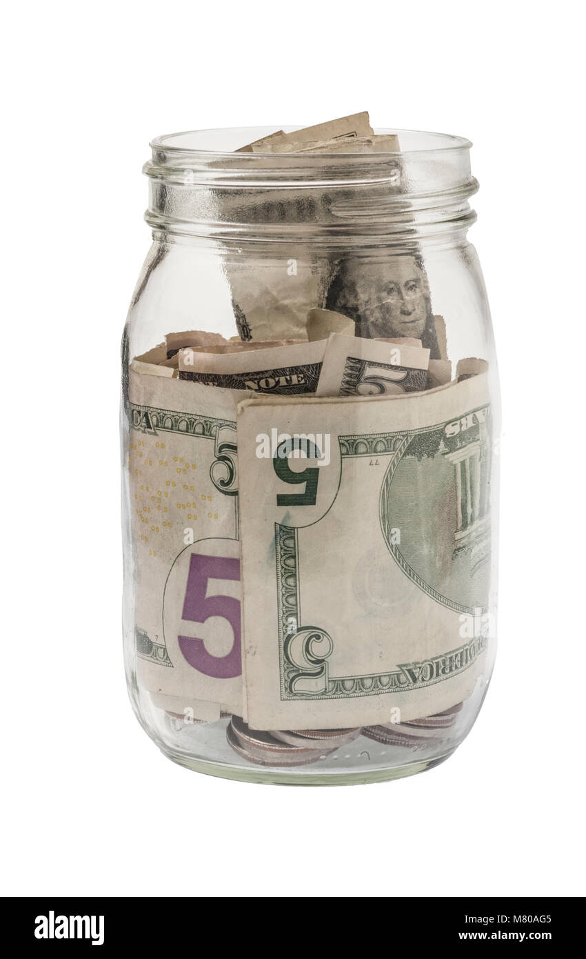 A glass tip jar filled with American five dollar bills isolated on a white background Stock Photo