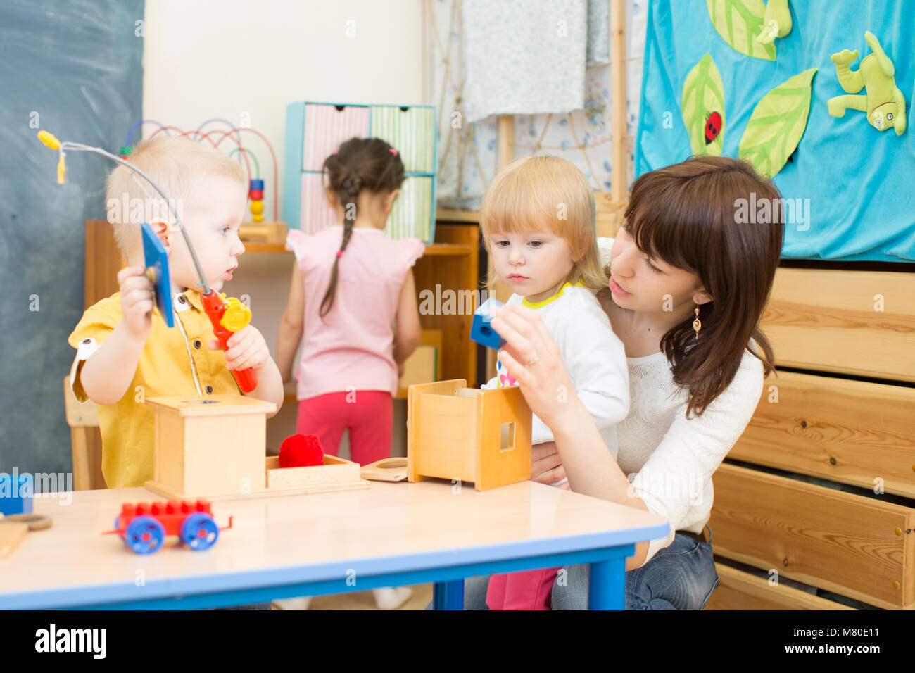 kids group playing with teacher in day care centre playroom Stock Photo