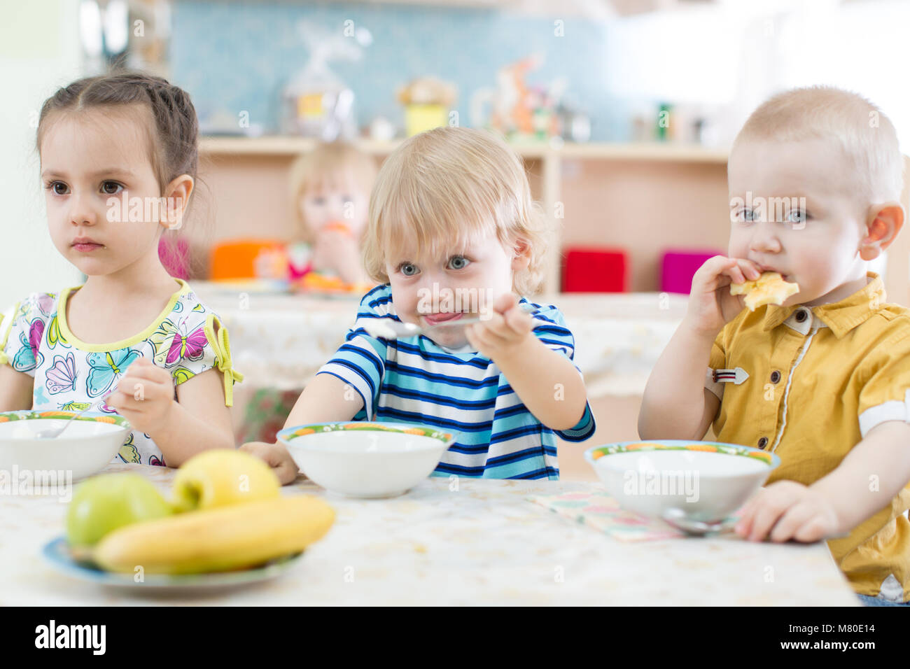 Kids have lunch in kindergarten or day care centre Stock Photo