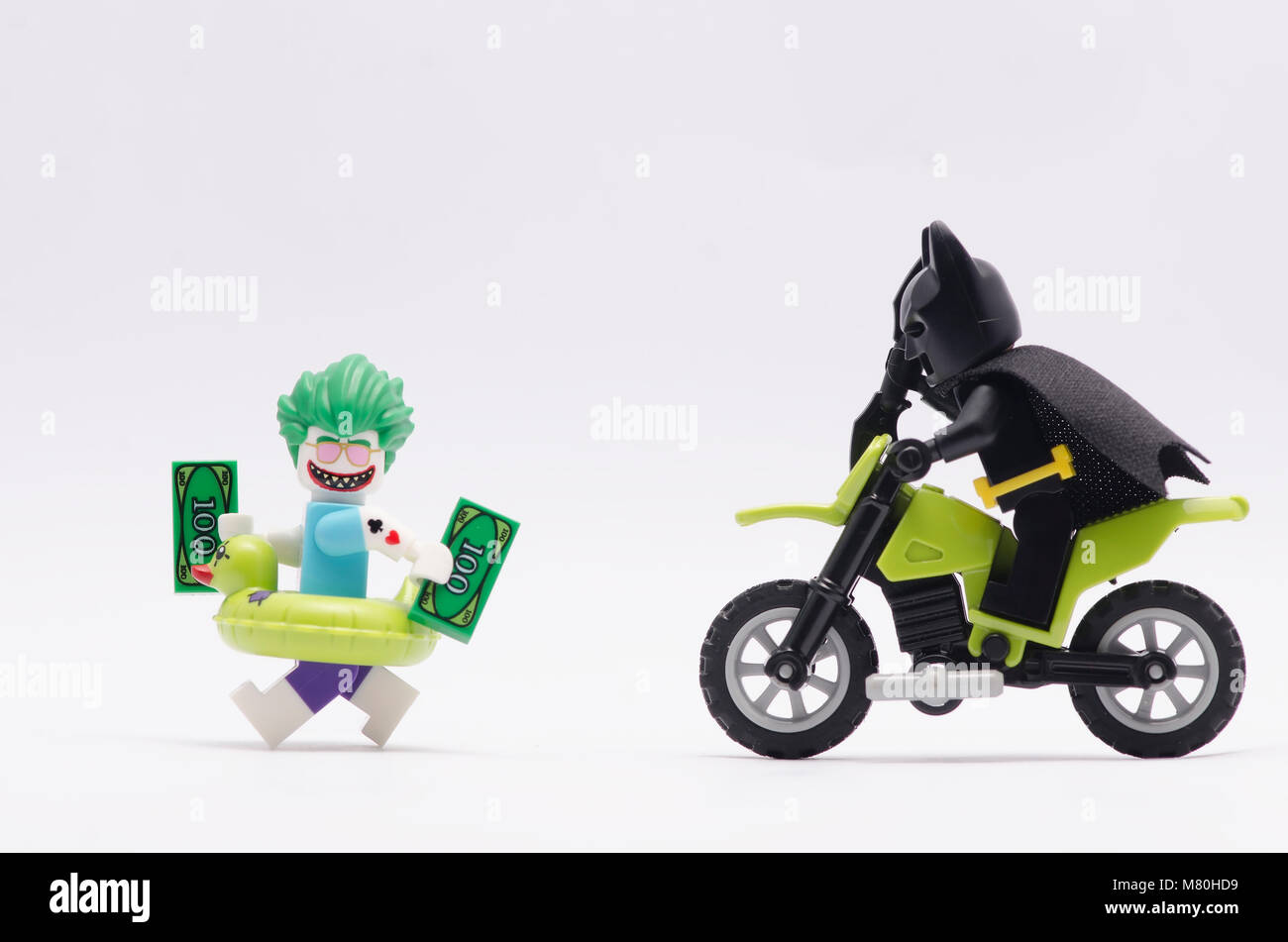 lego batman chasing joker running with money, isolated on white