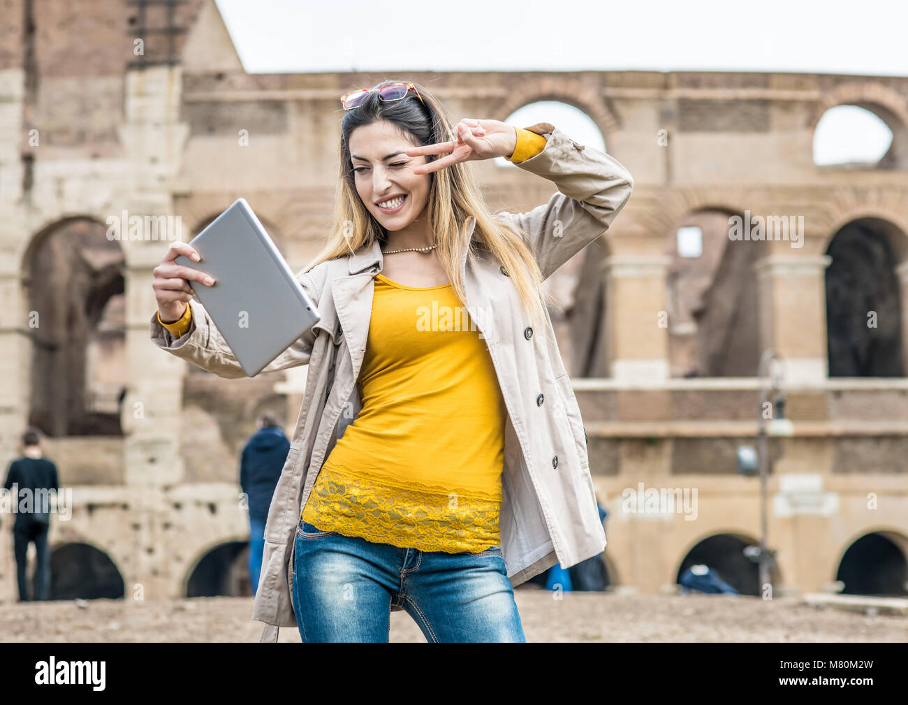 Young pretty tourist woman smiling doing self portrait, in background Colosseum monument in Rome Italy Stock Photo