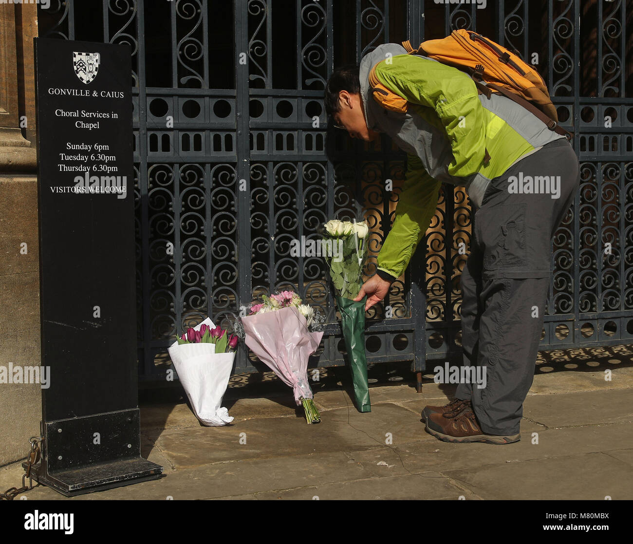 A man lays flowers outside Gonville and Caius College, Cambridge, after the death of the leading British scientist, Professor Stephen Hawking, who had been a Fellow of the college for more than 50 years. Stock Photo