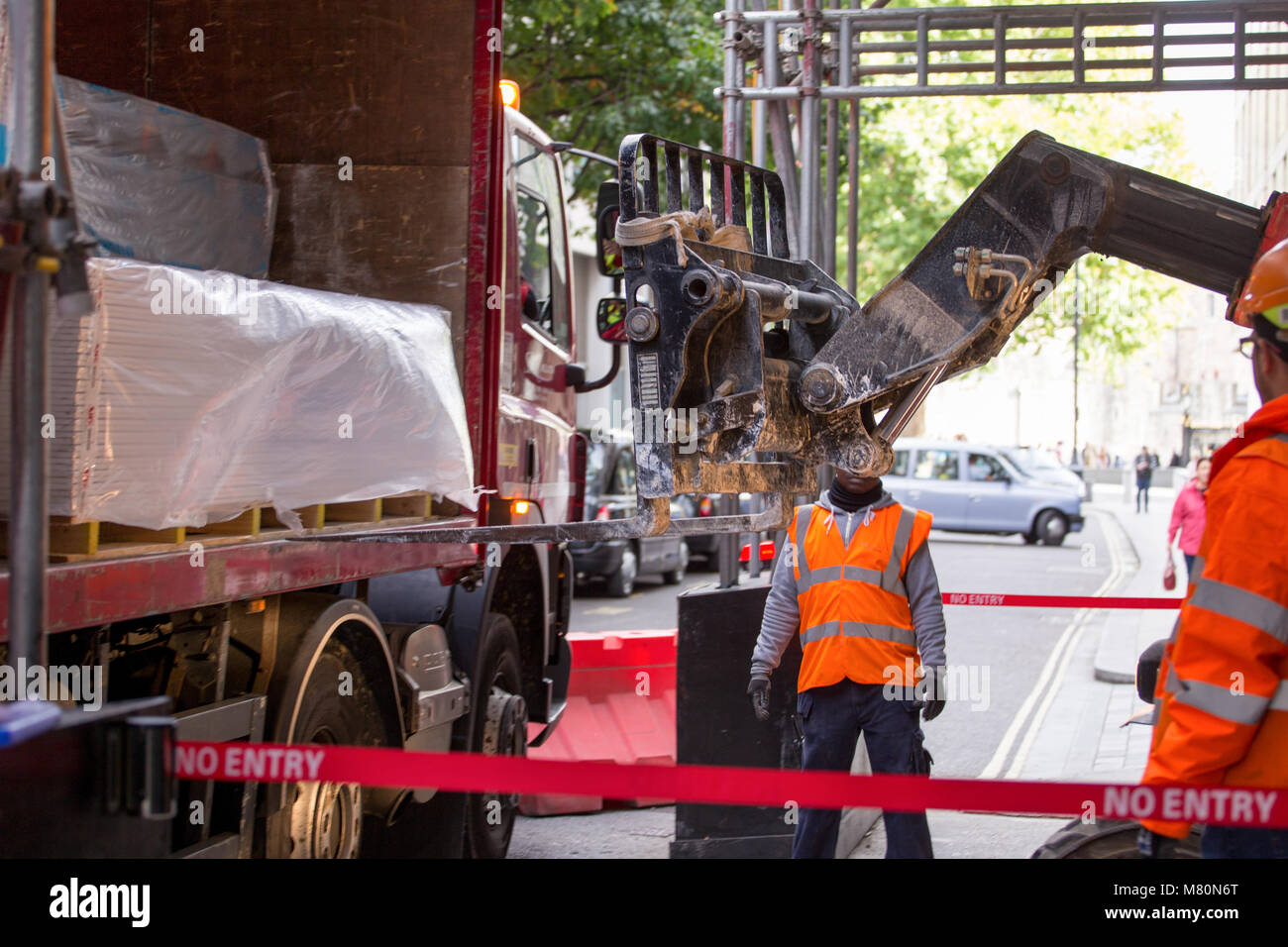 Workmen loading or unloading a curtain side lorry's cargo with a forklift truck Stock Photo