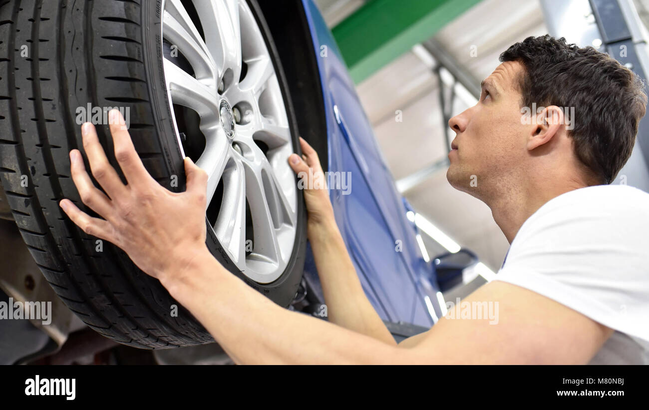 tyre change in a car repair shop - worker assembles rims on the vehicle Stock Photo