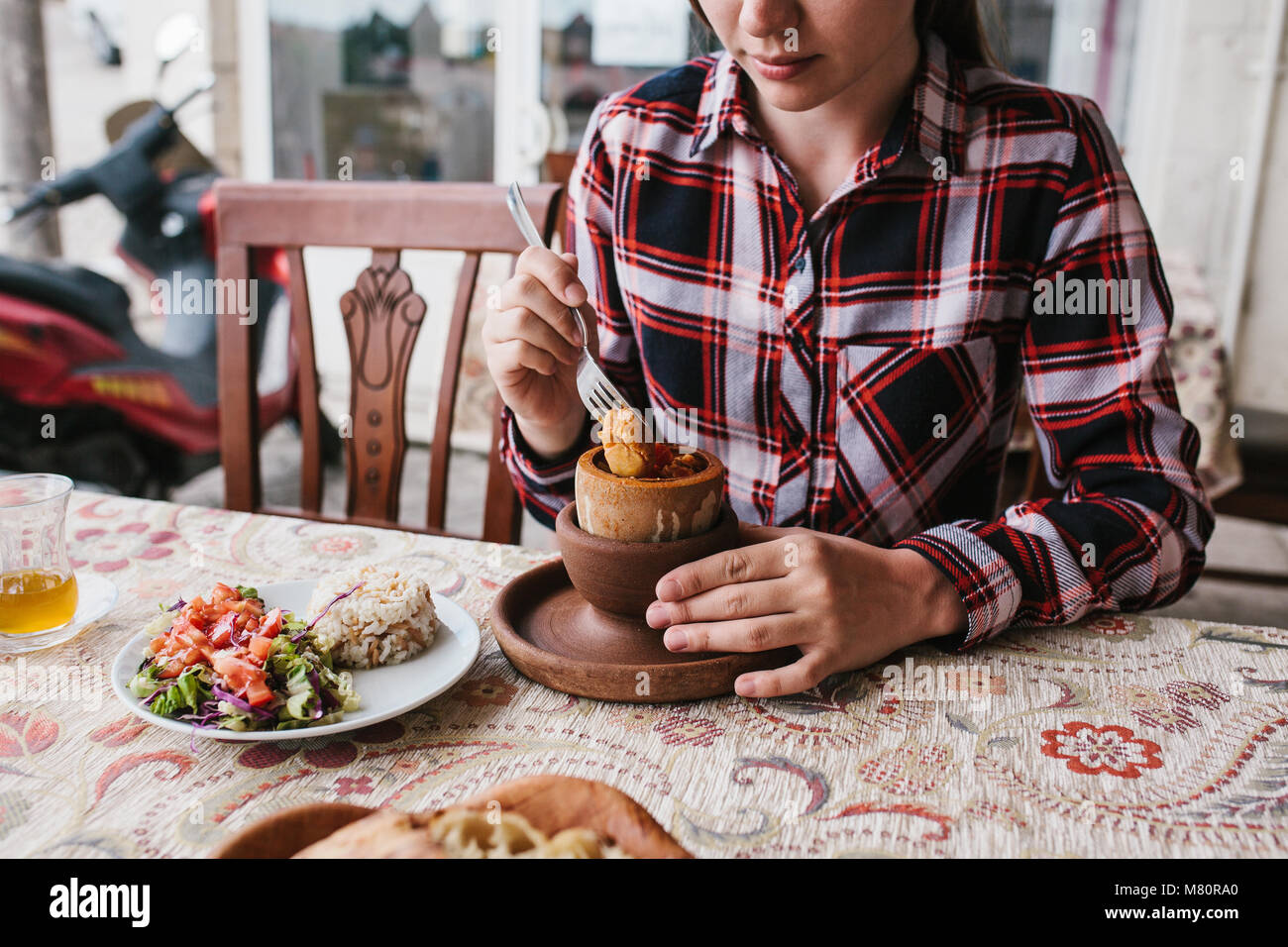 A restaurant visitor eats a national Turkish dish in a pot that is broken before being consumed called Testi-kebab. Stock Photo