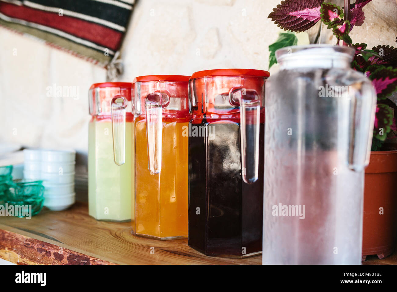 Closeup glass jugs with variety of fruit and berry drinks with red