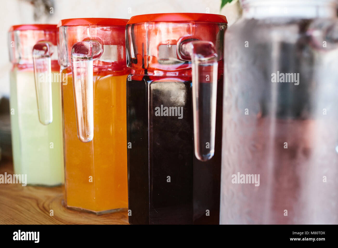 Closeup glass jugs with variety of fruit and berry drinks with red