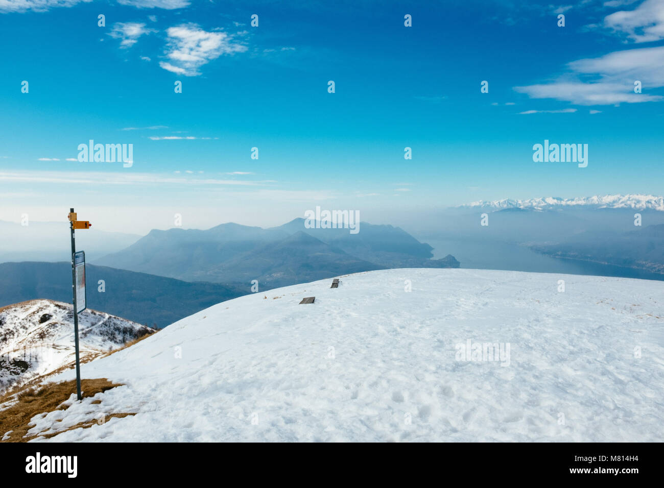 Landscape view of Lake Maggiore from the prealpine mountains, top of Monte Lema in winter with snow, yellow signs indicate the trails Stock Photo