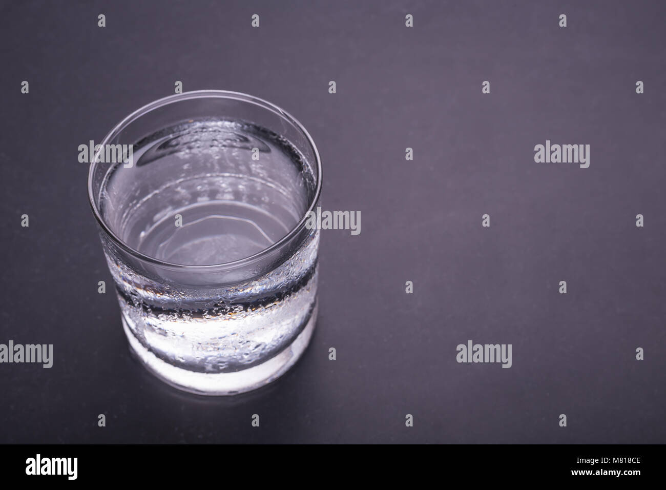 Close up glass of cold water on black table background. Top view with ...