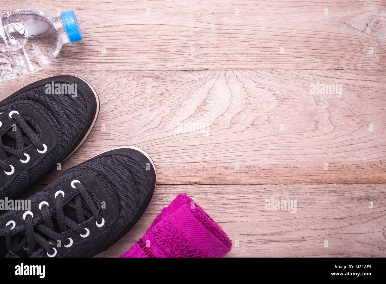 Black Running / Sneaker shoe, water bottle and towel on brown wooden floor. Exercise concept. Top view Stock Photo