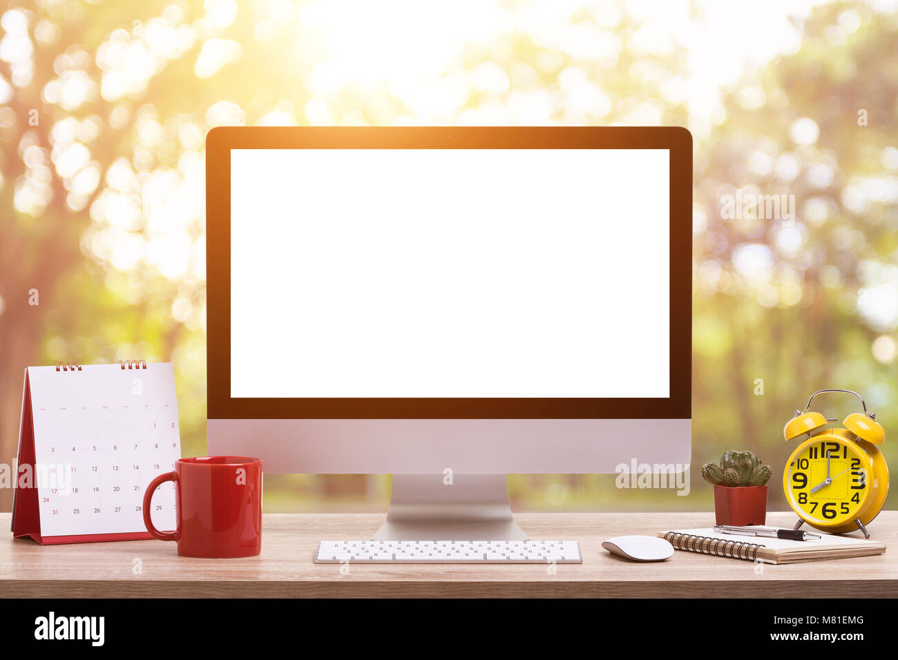 Modern desktop computer, Coffee cup, alarm clock, notebook and calendar on wooden table and abstract light blur and bokeh background. Saved with clipp Stock Photo