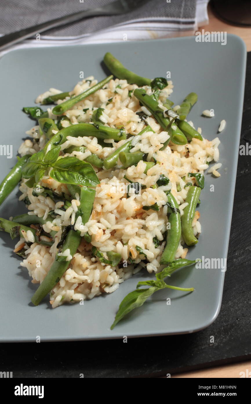 Risotto with green beans and basil leaves on a rectangular dish Stock