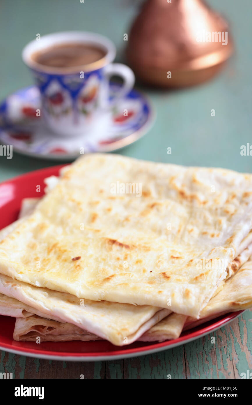 Stack of gozleme, the traditional Turkish pastry with cheese against a cup of coffee and cezve Stock Photo