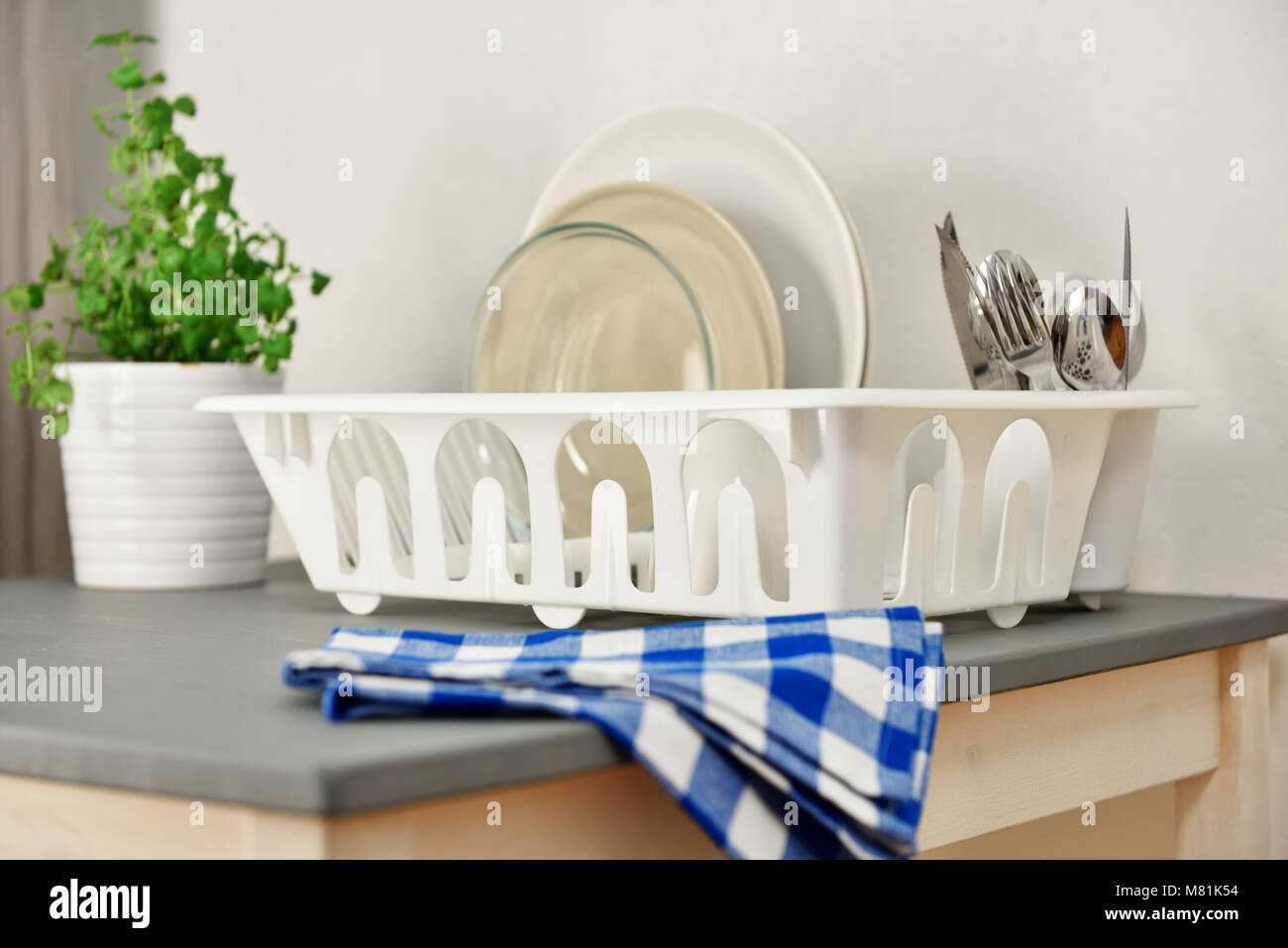 https://c8.alamy.com/comp/M81K54/dish-drainer-with-plates-and-silverware-on-a-table-focus-on-the-dish-M81K54.jpg