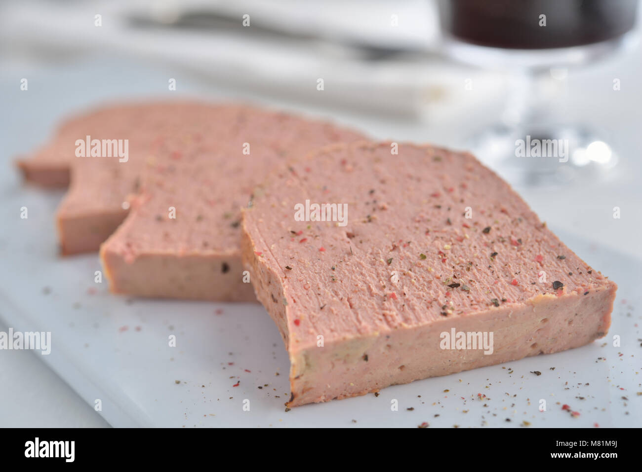 Slices of meat pate on the white plate. Selective focus on the front edge Stock Photo