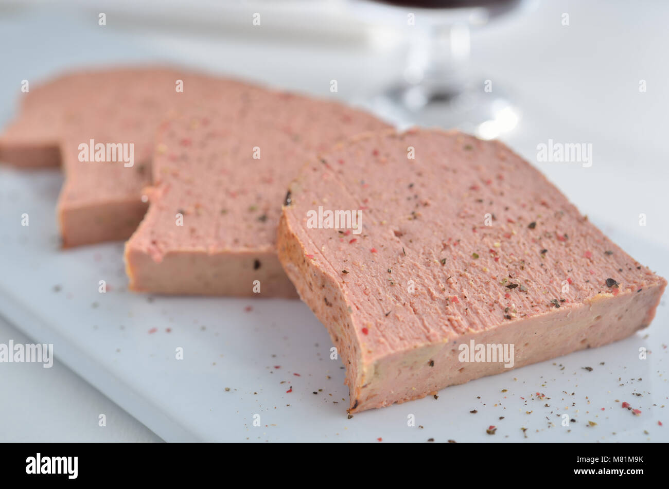 Slices of meat pate on the white plate. Selective focus on the front edge Stock Photo