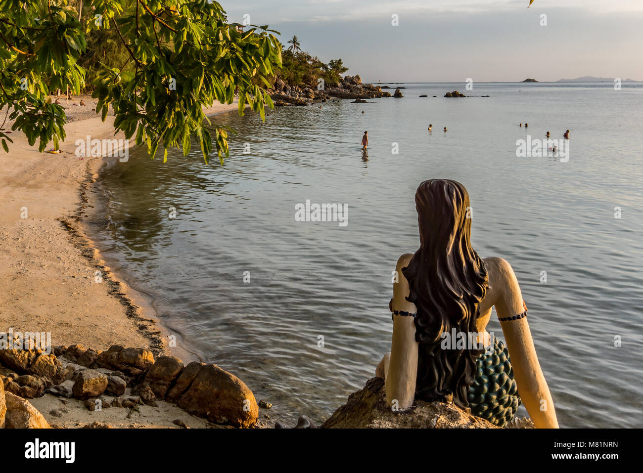 Little Maermaid sits on a cliff in the sunset and looks over the sea, Haad Son, Koh Pangan, Thailand, May 8, 2016, Stock Photo