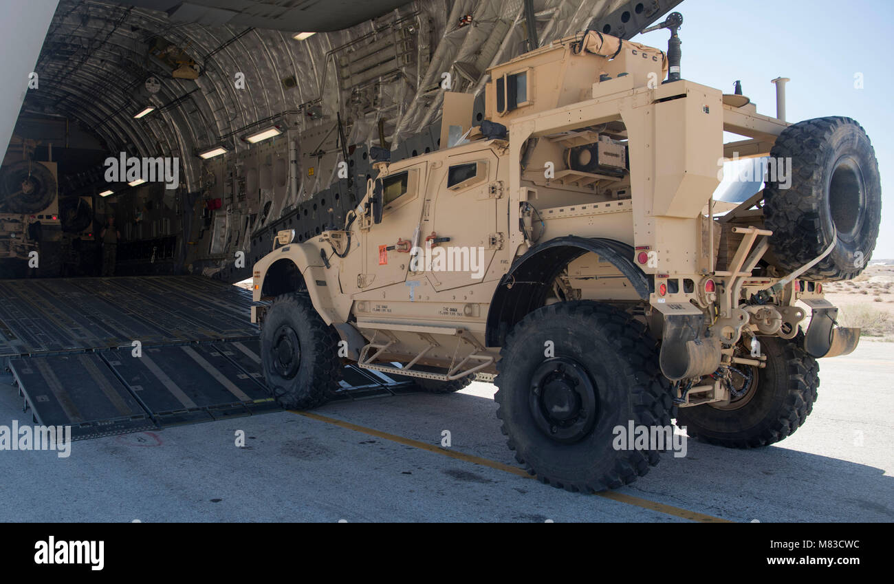 Mine-resistant ambush protected vehicles are loaded onto a C-17 Globemaster III at an undisclosed location in Southwest Asia March 7, 2018. MRAPS are able to provide protection for service members against roadside threats like improvised devices and mines. (U.S. Air Force photo by Senior Airman Krystal Wright) Stock Photo