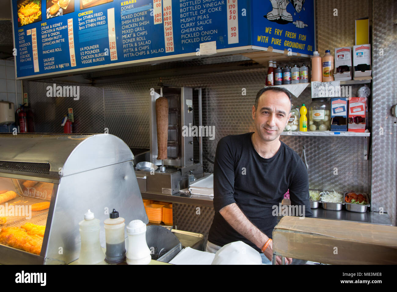 Man serving chips at a takeaway fish and chips restaurant Stock Photo