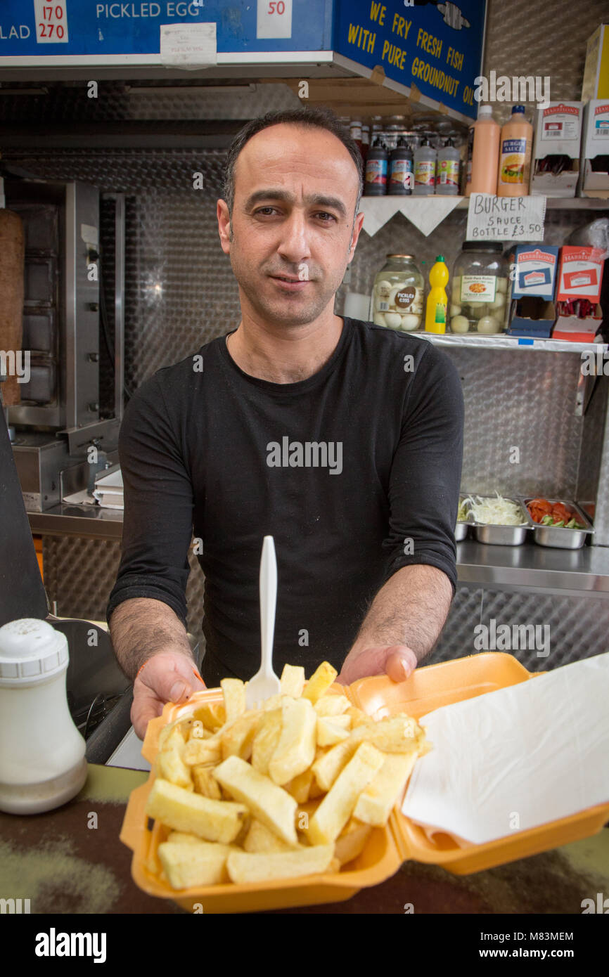 Man serving chips at a takeaway fish and chips restaurant Stock Photo