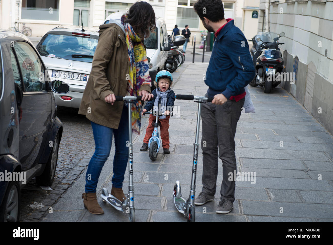 Parents with crying child and push scooters in street, Paris, France Stock Photo
